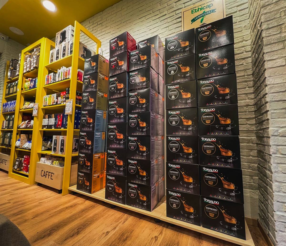 Gli scaffali gialli del negozio con le confezioni di capsule